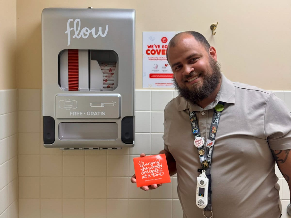 Javier Vicente standing next to Aunt Flow dispenser